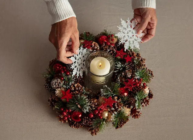 Corona de Adviento decorativa con vela al centro, piñas, ramas y adornos navideños rojos de Kemiyat Importadora.